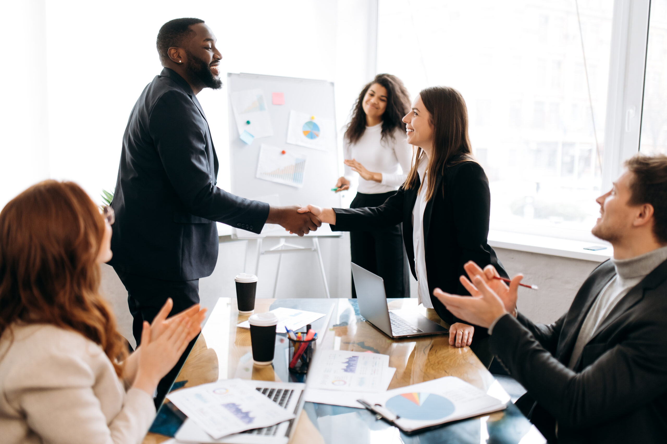 Sales professionals shaking hands with a client during a face-to-face outreach